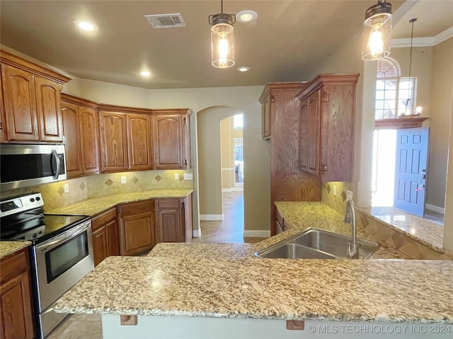 kitchen with appliances with stainless steel finishes, backsplash, crown molding, sink, and decorative light fixtures