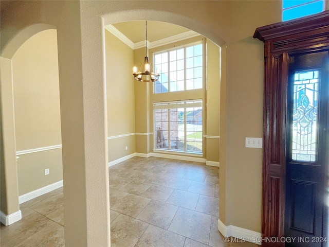 tiled foyer entrance featuring a chandelier, ornamental molding, and a healthy amount of sunlight