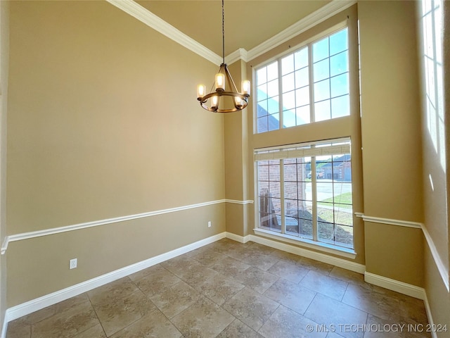 unfurnished room featuring a wealth of natural light, crown molding, a high ceiling, and a notable chandelier