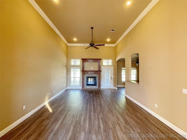 unfurnished living room featuring hardwood / wood-style flooring, ceiling fan, a towering ceiling, and crown molding