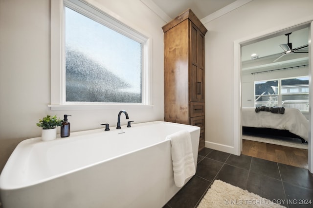 bathroom featuring tile patterned floors, a bathtub, ornamental molding, and a wealth of natural light