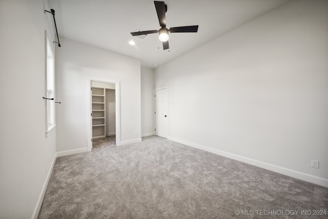 unfurnished bedroom with a spacious closet, ceiling fan, carpet floors, and lofted ceiling