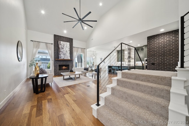 stairway featuring ceiling fan, wood-type flooring, a fireplace, and high vaulted ceiling