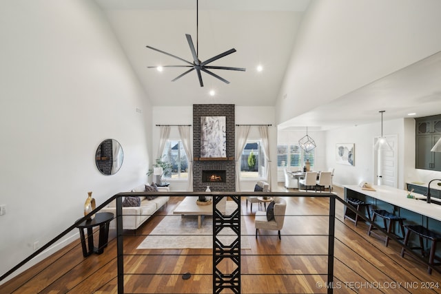 living room featuring a fireplace, dark hardwood / wood-style flooring, high vaulted ceiling, and ceiling fan