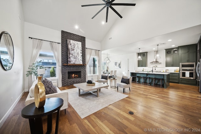 living room with ceiling fan, a healthy amount of sunlight, wood-type flooring, and high vaulted ceiling