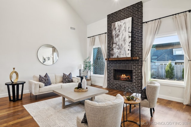 living room featuring dark hardwood / wood-style flooring, a brick fireplace, and vaulted ceiling