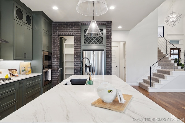 kitchen featuring light stone countertops, appliances with stainless steel finishes, sink, dark hardwood / wood-style floors, and hanging light fixtures