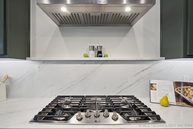 details with wall chimney exhaust hood and stainless steel gas cooktop