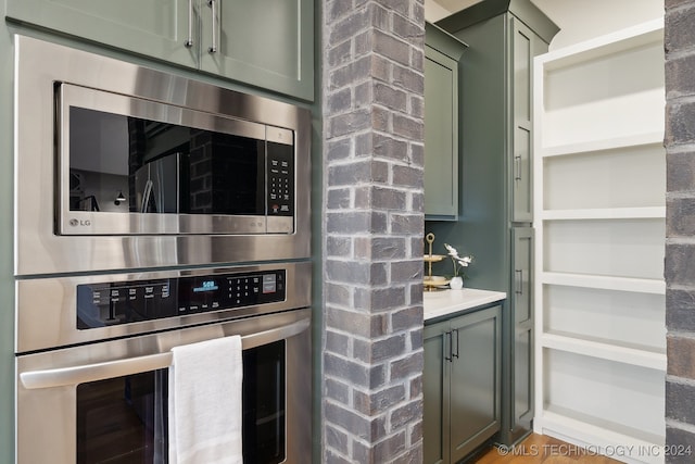 kitchen with green cabinets and appliances with stainless steel finishes