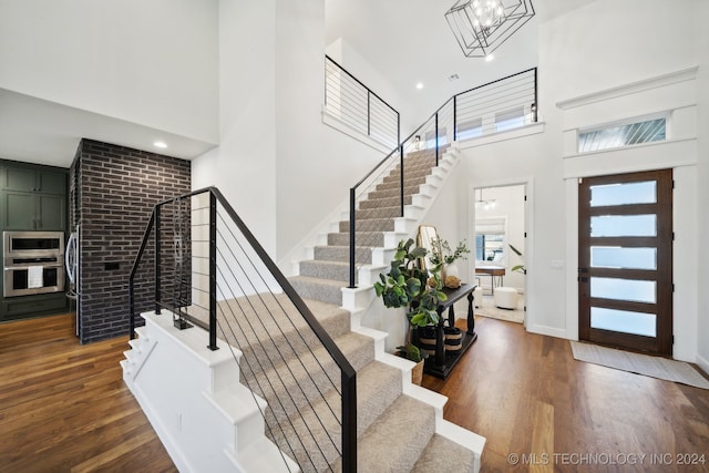 foyer with a high ceiling, dark wood-type flooring, and a notable chandelier