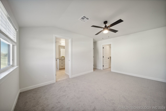 unfurnished bedroom featuring ensuite bathroom, ceiling fan, light colored carpet, and vaulted ceiling