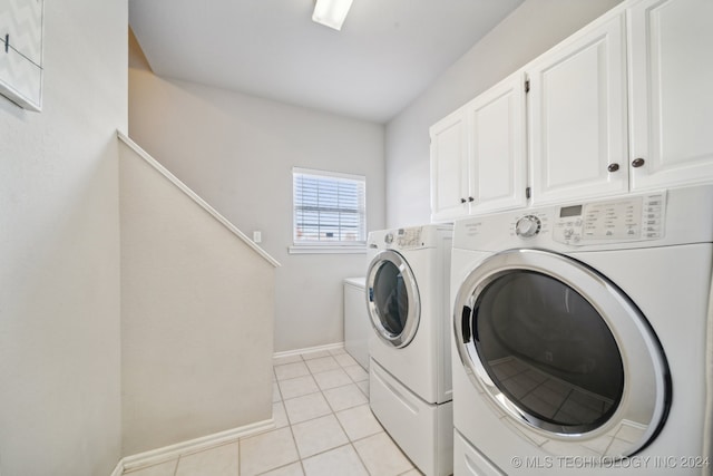 washroom with cabinets, light tile patterned floors, and washing machine and clothes dryer