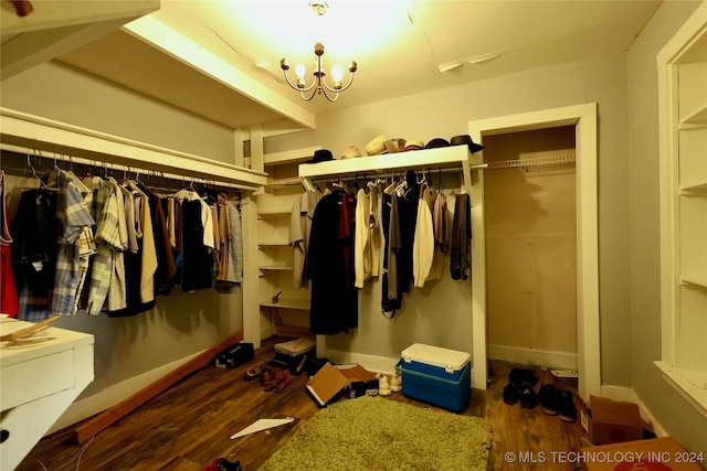 walk in closet featuring a notable chandelier and dark wood-type flooring