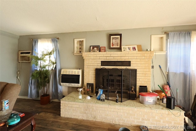 living room with a wall unit AC, heating unit, a fireplace, and hardwood / wood-style floors