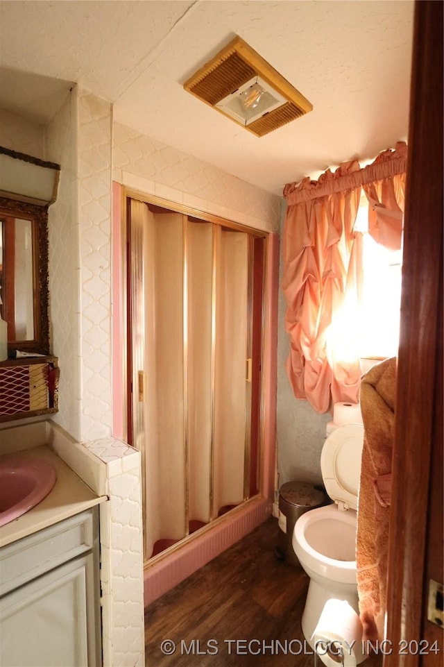 bathroom with toilet, hardwood / wood-style floors, vanity, and walk in shower