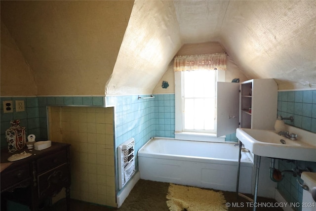 bathroom with vaulted ceiling, a textured ceiling, tile walls, a tub, and heating unit