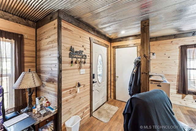 foyer with light wood-type flooring, wooden walls, and wooden ceiling