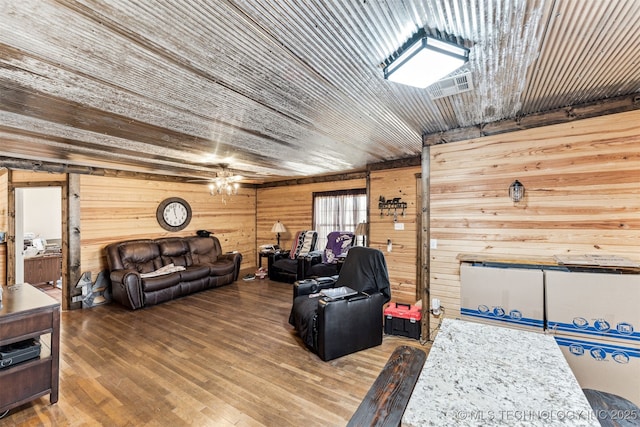 living room with hardwood / wood-style flooring, ceiling fan, and wooden walls