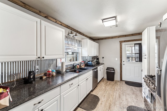 kitchen featuring white cabinetry, sink, light hardwood / wood-style flooring, a textured ceiling, and appliances with stainless steel finishes