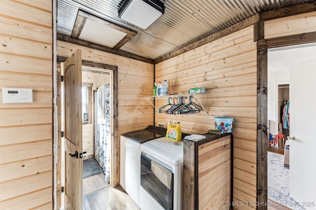 clothes washing area featuring hardwood / wood-style flooring, washer and dryer, wood walls, and wooden ceiling