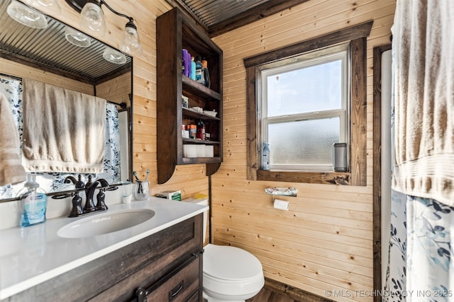 bathroom with wooden walls, vanity, and toilet