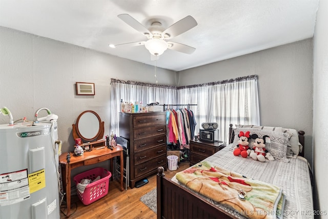 bedroom featuring ceiling fan, light wood-type flooring, and water heater