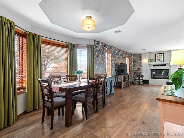 dining space with wood-type flooring, a wealth of natural light, and built in shelves