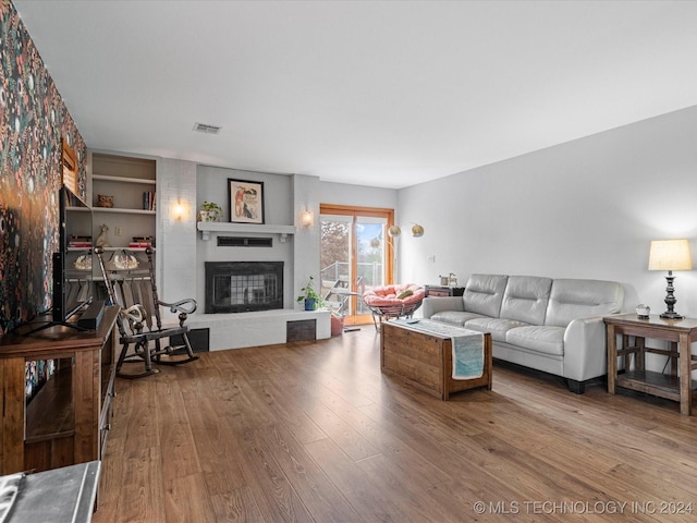 living room with hardwood / wood-style flooring and a brick fireplace