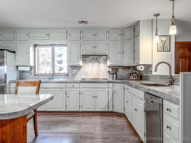 kitchen with white cabinets, sink, light hardwood / wood-style flooring, appliances with stainless steel finishes, and decorative light fixtures