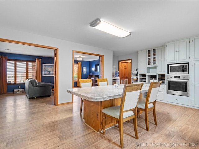 kitchen featuring white cabinets, appliances with stainless steel finishes, light hardwood / wood-style flooring, and a kitchen breakfast bar