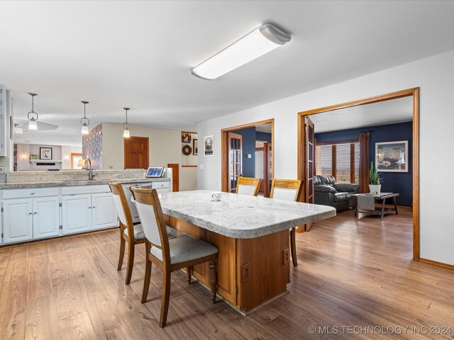 kitchen featuring a kitchen breakfast bar, white cabinets, light hardwood / wood-style floors, a kitchen island, and hanging light fixtures