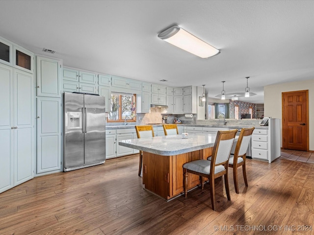 kitchen featuring kitchen peninsula, stainless steel fridge, a kitchen bar, dark hardwood / wood-style floors, and a kitchen island