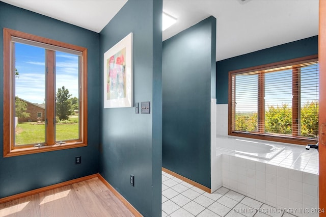 bathroom featuring tiled tub, plenty of natural light, and hardwood / wood-style floors