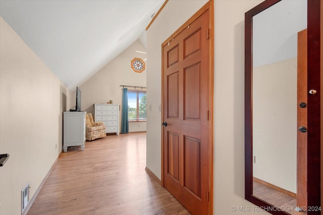 hallway featuring high vaulted ceiling and light hardwood / wood-style flooring