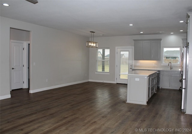 kitchen featuring a center island, sink, hanging light fixtures, dark hardwood / wood-style floors, and stainless steel fridge