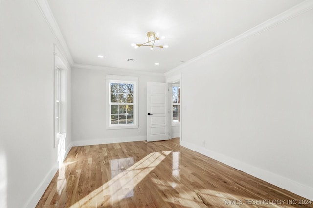 empty room featuring light hardwood / wood-style flooring, an inviting chandelier, and ornamental molding