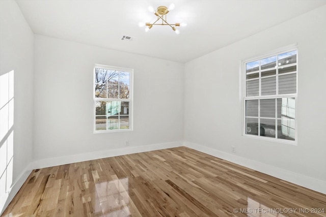 empty room featuring a chandelier and hardwood / wood-style flooring