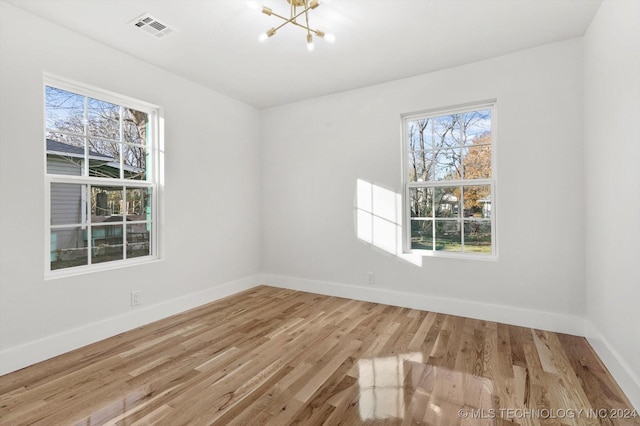 unfurnished room with a notable chandelier and light hardwood / wood-style flooring