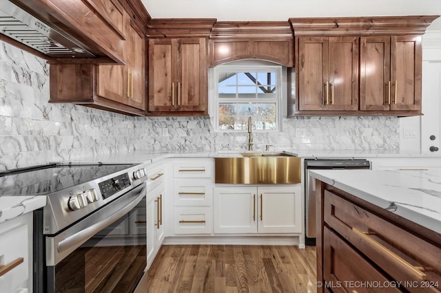 kitchen with premium range hood, light hardwood / wood-style flooring, light stone counters, white cabinetry, and stainless steel appliances