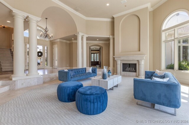 3520 W 77th St S, Tulsa, OK 74132 - living area with decorative columns, crown molding, arched walkways, a fireplace, and a towering ceiling