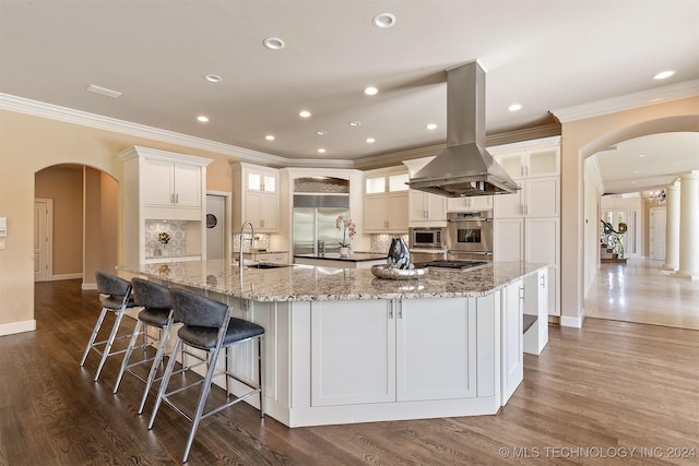 3520 W 77th St S, Tulsa, OK 74132 - kitchen featuring island range hood, arched walkways, built in appliances, a spacious island, and crown molding