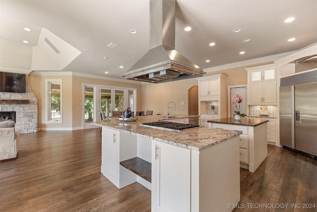 kitchen with island exhaust hood, appliances with stainless steel finishes, a spacious island, white cabinets, and dark hardwood / wood-style floors