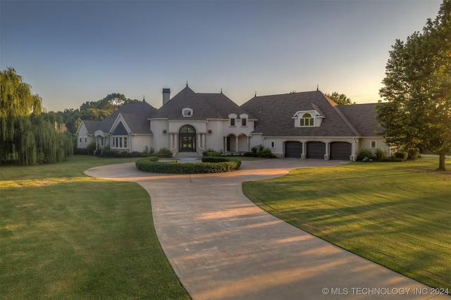 3520 W 77th St S, Tulsa, OK 74132 - french country home featuring curved driveway, a chimney, a yard, stucco siding, and an attached garage