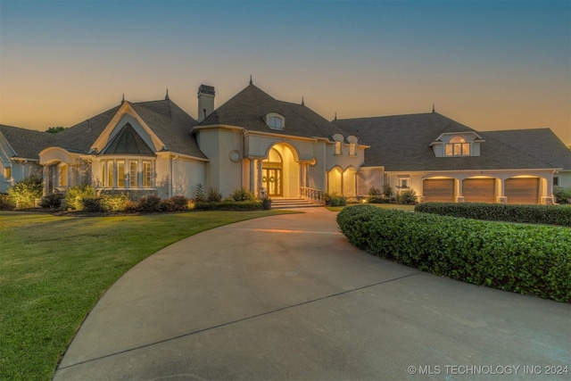 french country home with a yard, french doors, and a garage