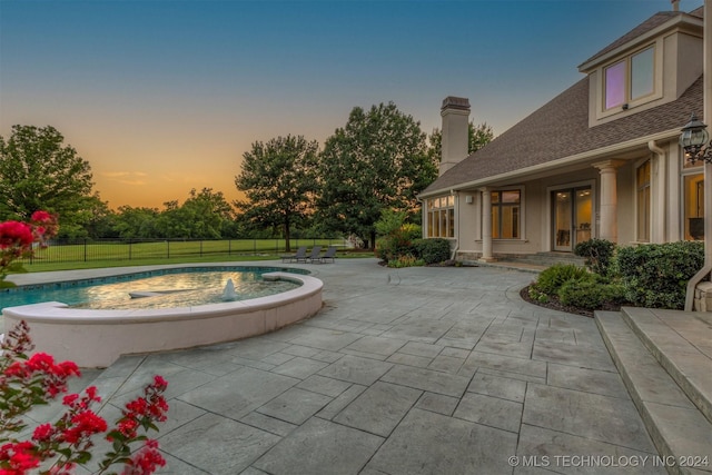 pool at dusk featuring a patio