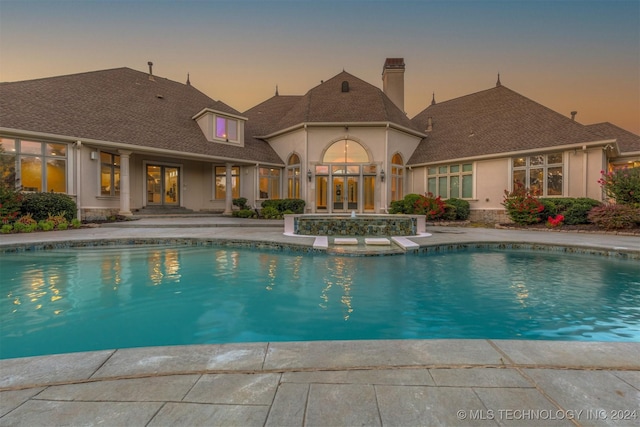 pool at dusk featuring french doors