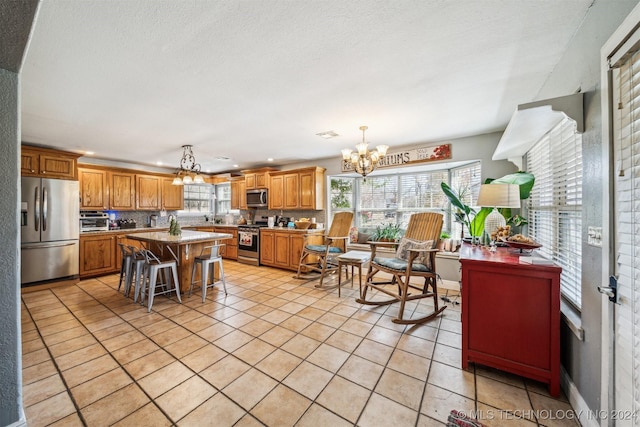 kitchen featuring a center island, an inviting chandelier, a breakfast bar area, decorative light fixtures, and stainless steel appliances