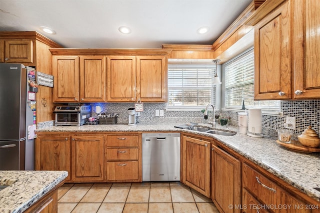 kitchen with light stone counters, sink, light tile patterned floors, and stainless steel appliances