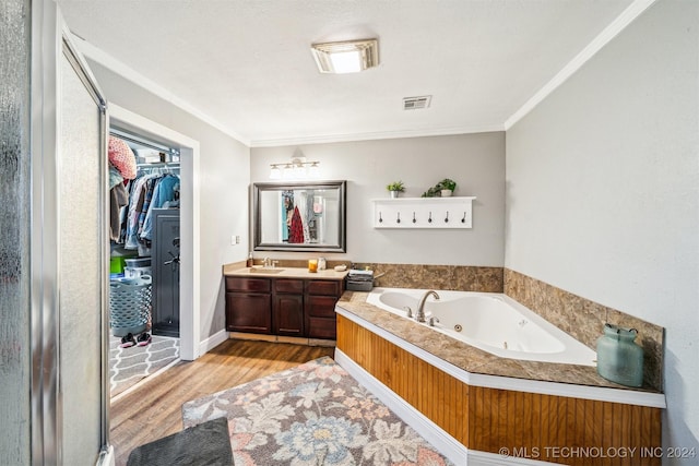 bathroom with a washtub, hardwood / wood-style floors, vanity, and crown molding