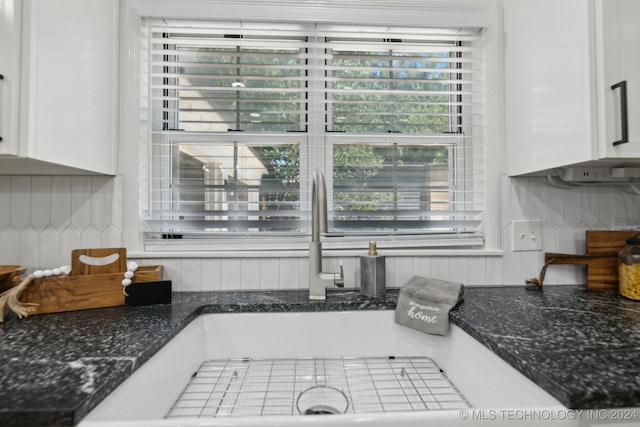 details with tasteful backsplash, white cabinetry, and sink